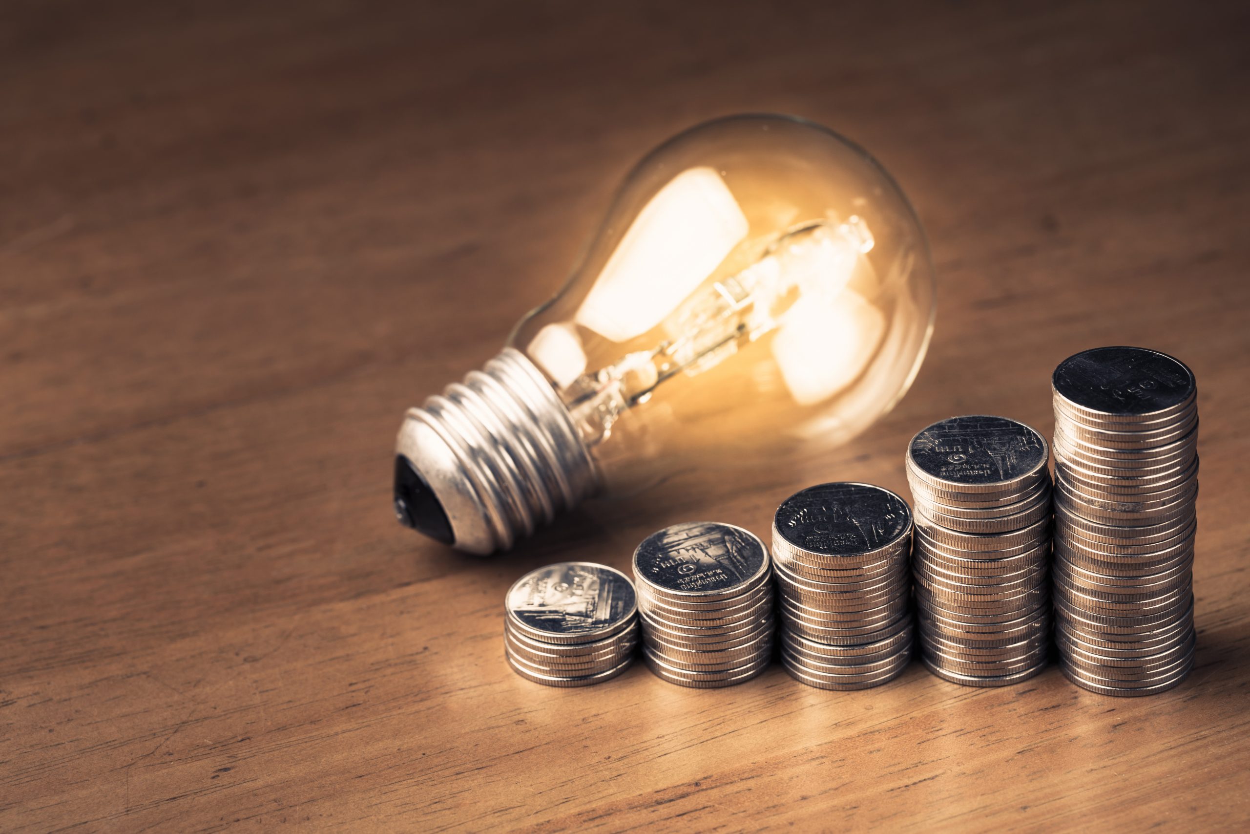 Heap coins stair with glowing light bulb